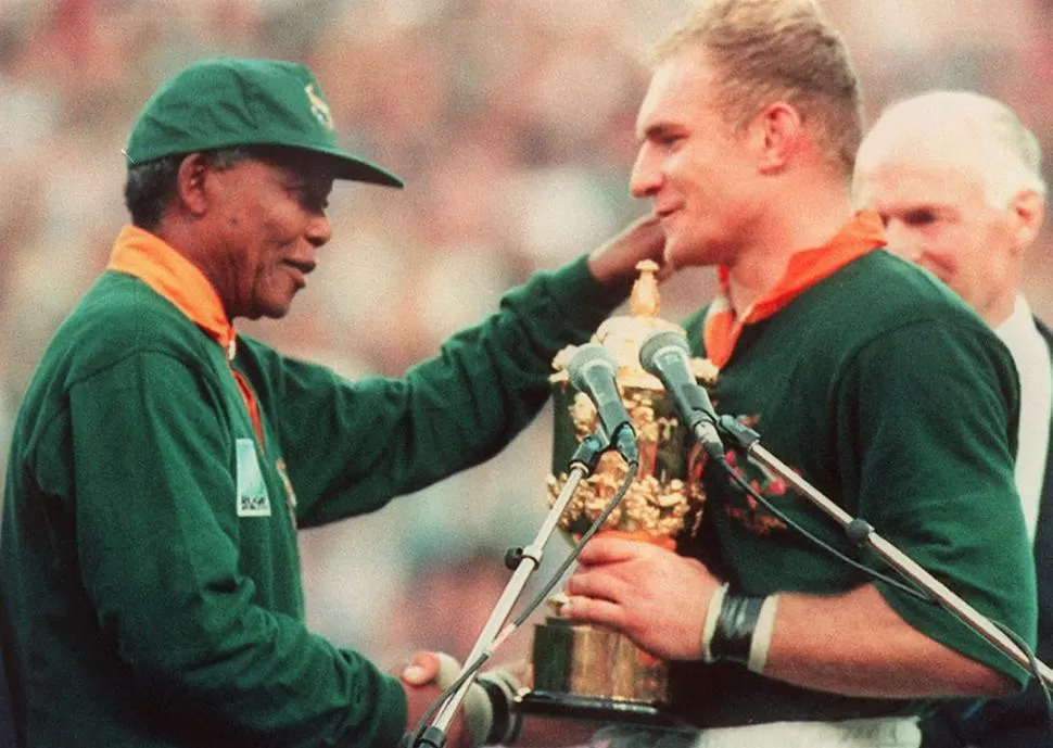 ESE MOMENTO. Mandela entrega la copa del Mundial de Rugby de 1995 a Francois Pienaar, capitán de los Springboks, mientras todo el estadio lo ovaciona para la historia. LA GACETA / ARCHIVO