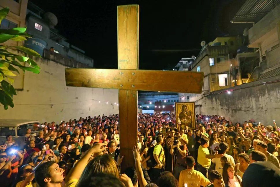EN LA FAVELA. La cruz peregrina y la imagen de la Virgen María recorrieron ayer Rocinha, un barrio pobre. EFE 