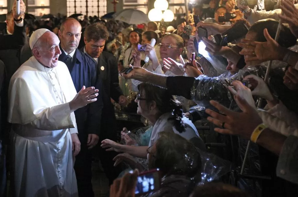 SALUDOS BAJO LA LLUVIA. El Papa Francisco bromea con los fieles.  