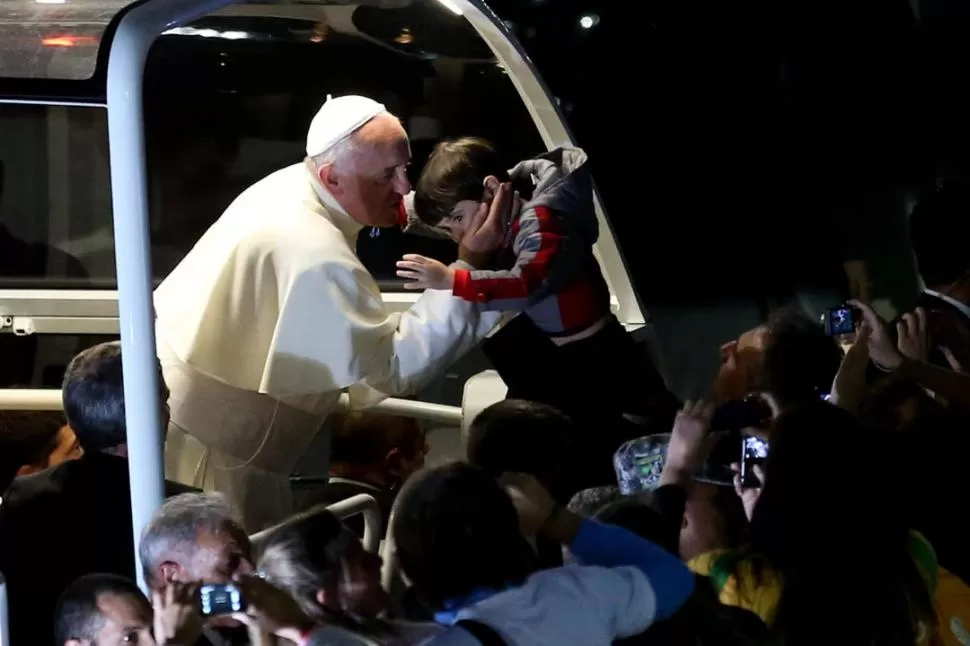 AFECTO. Francisco recibe a un niño poco antes del Vìa Crucis. Luego de dos dìas de lluvia, el clima ayudó para que los peregrinos se acerquen al Papa. FOTOS DE EFE - REUTERS