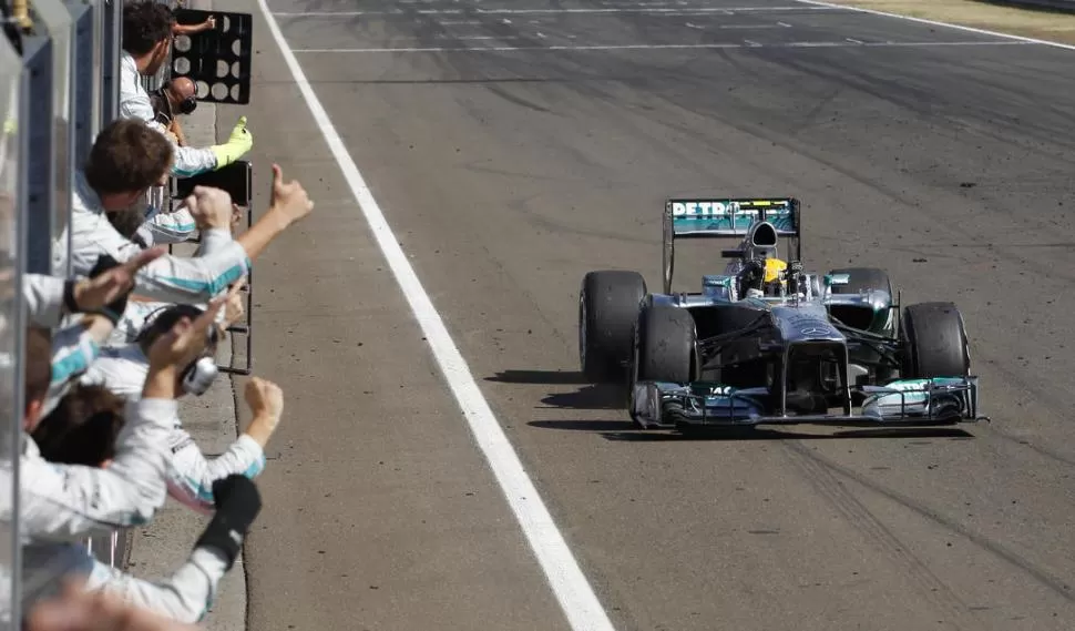 LOS PULGARES ARRIBA. El equipo Mercedes saluda al británico Lewis Hamilton luego de haber cruzado la meta con su Mercedes. La victoria fue inesperada, pero fue festejada con mucha algarabía. 