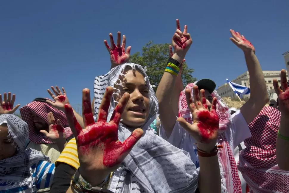 PROTESTA. Familiares de víctimas de atentados palestinos muestran sus manos con sangre de sus parientes. REUTERS