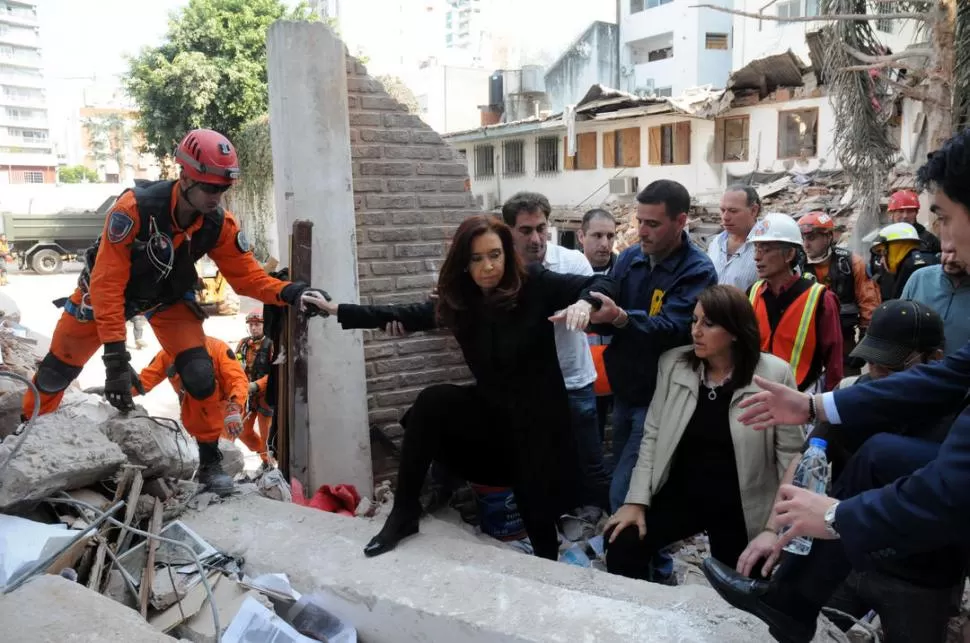 DE VISITA. Asistida por un rescatista y un colaborador, Cristina Fernández trepó ayer a la zona del desastre. TELAM