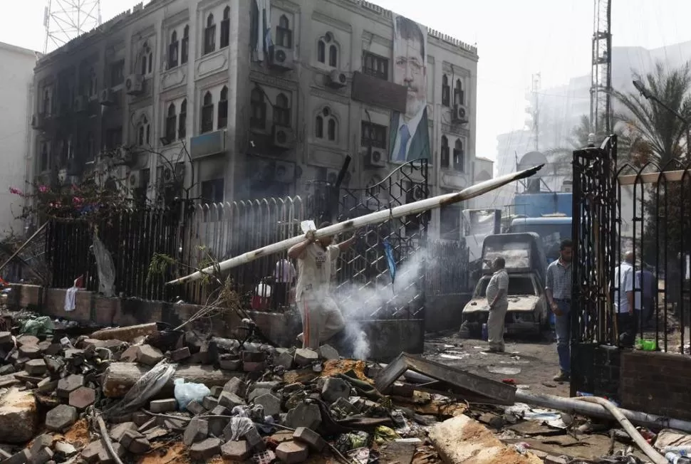 DESTRUCCIÓN. Un empleado retira objetos de unos de los edificios gubernamentales incendiados en El Cairo. REUTERS