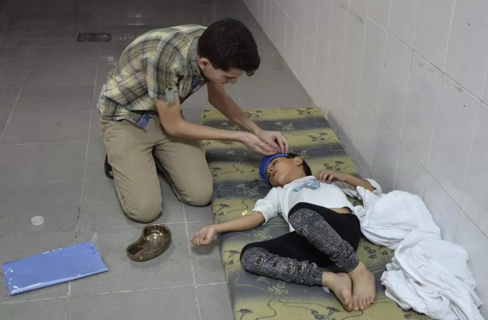 ENVENENADO. Un niño es atendido en el pasillo de un hospital cerca de Damasco, afectado por los gases.  REUTERS