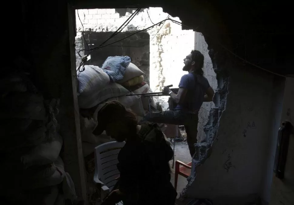 EN COMBATE. Combatientes rebeldes defienden una posición en la localidad de Deir al Zor, en el noreste sirio. REUTERS