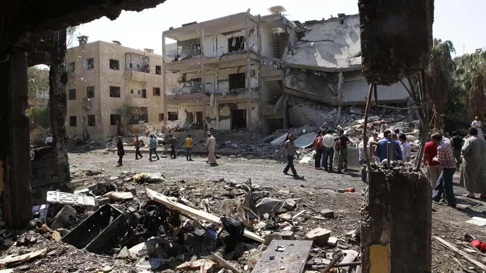 BUSQUEDA. Entre los escombros, pobladores de la ciudad de Raqqa, buscan sus pertenencias luego de que explotó un coche bomba. REUTERS

