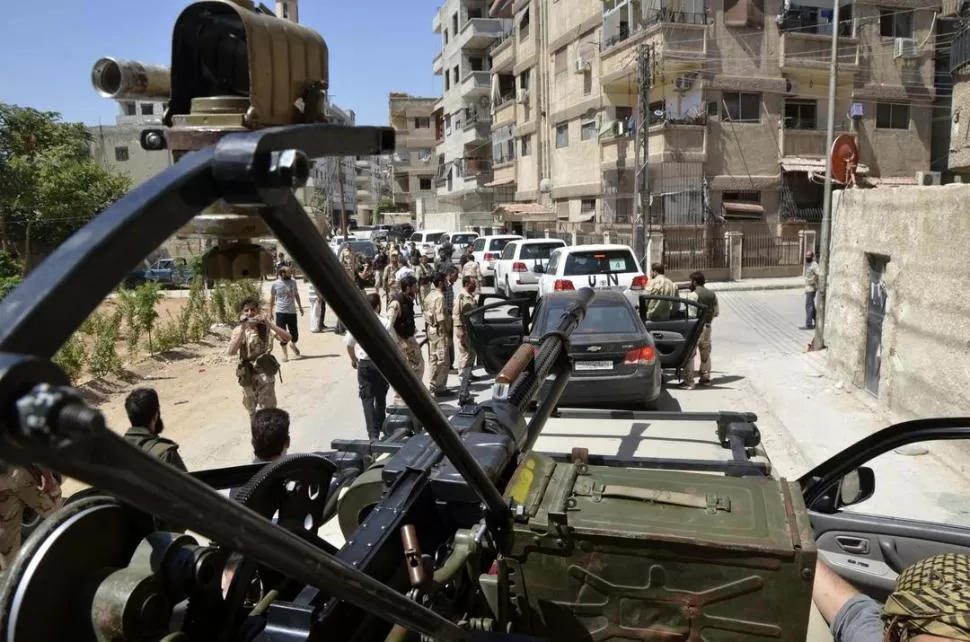 INSPECCIÓN. Los expertos de la ONU, acompañados por soldados rebeldes, buscan pruebas del ataque químico en el distrito de Zamalka, cerca de Damasco. REUTERS
