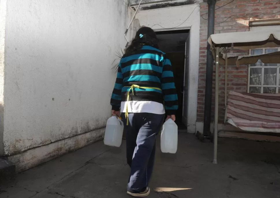 RESERVA. María Julia, empleada de los García, carga dos bidones llenos de agua. Las horas de gracia son entre la 1 y las 8 de la mañana. 