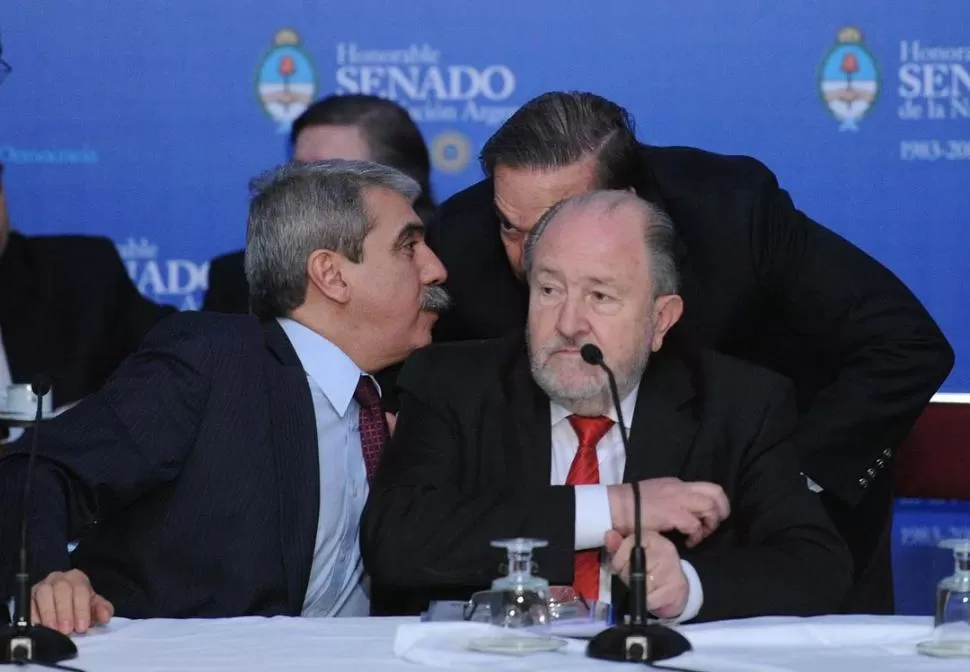 DELIBERACIONES. Los senadores oficialistas Aníbal Fernández y Miguel Pichetto (casi tapado por el justicialista Carlos Verna) dialogan en el Senado. TELAM