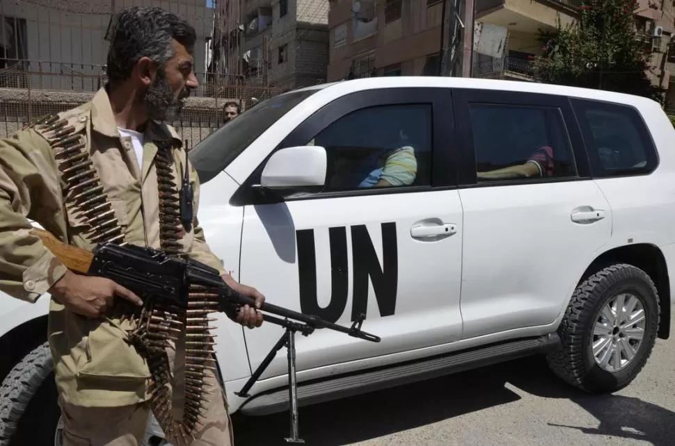 EN DAMASCO. Un combatiente rebelde custodia un vehículo en el que se desplazaban los inspectores. REUTERS