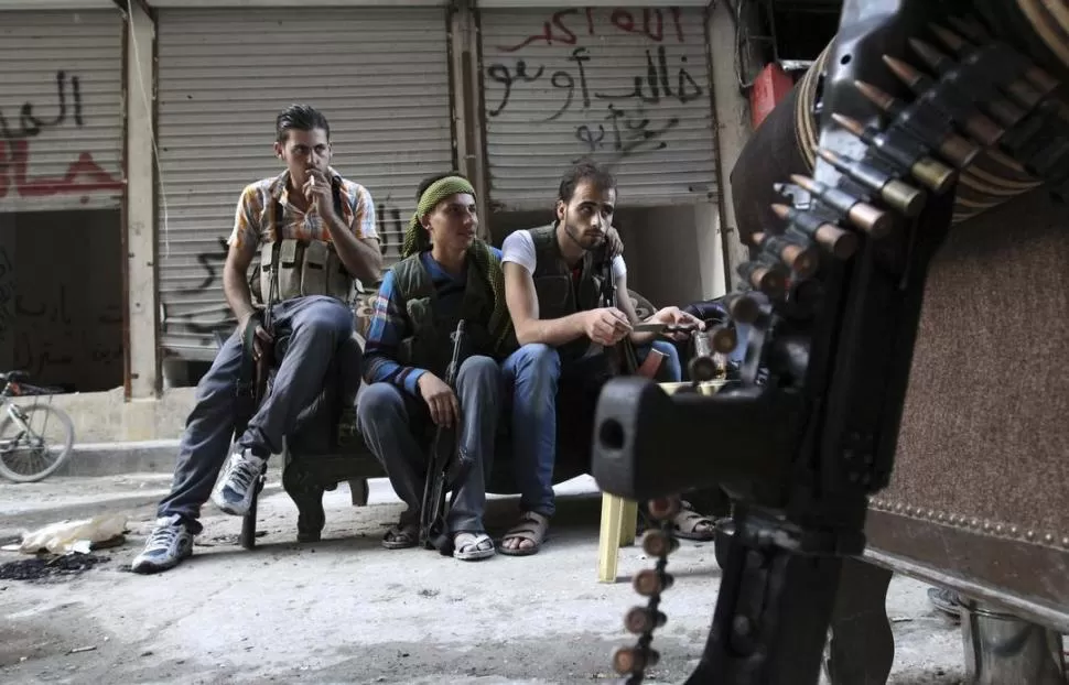 PAUSA EN EL COMBATE. Milicianos rebeldes esperan órdenes para atacar en la ciudad de Ashrafieh, en Alepo. REUTERS