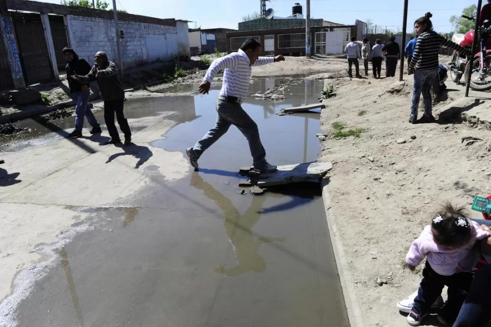 A LOS SALTOS. El vecino Fabián Carrazano muestra cómo hay que cruzar la Guatemala para evitar mojarse las zapatillas en el río que corre por la calle. LA GACETA / FOTO DE JORGE OLMOS SGROSSO