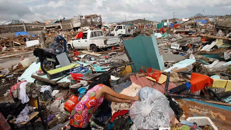 DEVASTADOR. Una mujer se seca su ropa cerca de miles de casas dañadas después de súper tifón Haiyan maltratadas Tacloban City, Filipinas. REUTERS