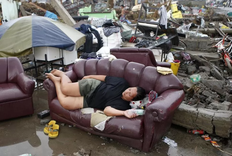 DESAMPARO. Una persona descansa en un sillón en medio de los restos dejados por el paso del tifón en la ciudad de Palo, en la provincia de Leyte. FOTOS REUTERS