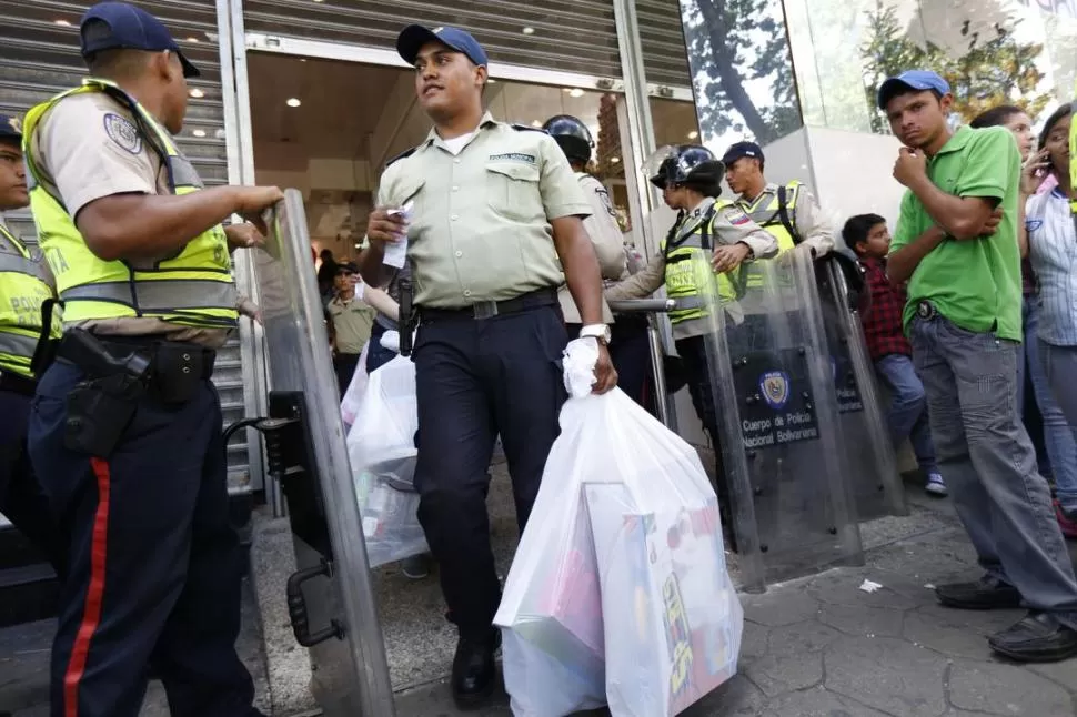 EN CARACAS. Un policía lleva su compra desde una tienda fiscalizada. REUTERS