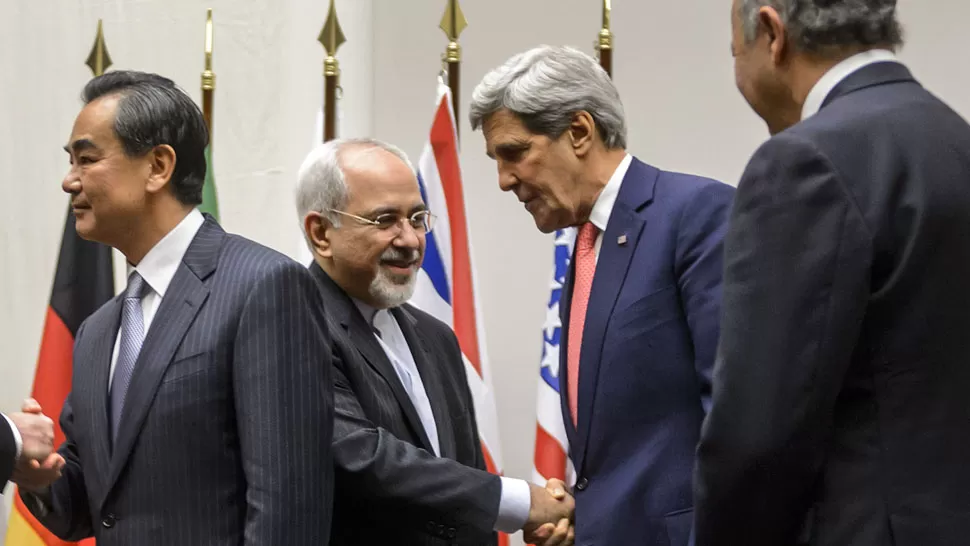 SALUDO. El canciller iraní Mohammad Javad Zarif estrecha la mano del secretario de Estado de EE.UU., John Kerry, luego de la firma para la suspensión temporal del programa nuclear irani. (Télam)