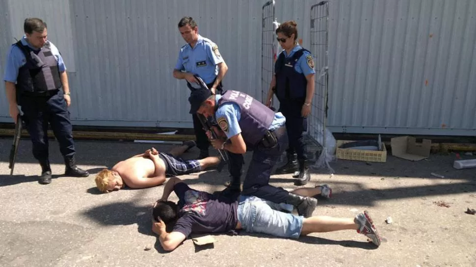 CULPABLES. Policías interrogan a dos detenidos luego del saqueo a un supermercado de la capital cordobesa. dyn