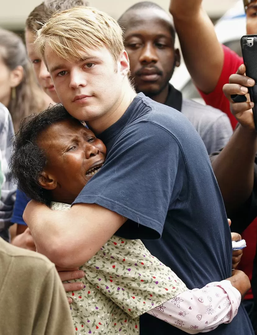 LO LOGRÓ. En la vereda de la casa de Nelson Mandela, una mujer negra es consolada por un joven blanco. reuters