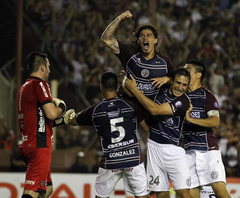 ARRIBA, CAMPEÓN. González, Izquierdoz y Goltz, buscan el abrazo de Blanco, que festeja a lo loco el 2-0 del “granate”. 