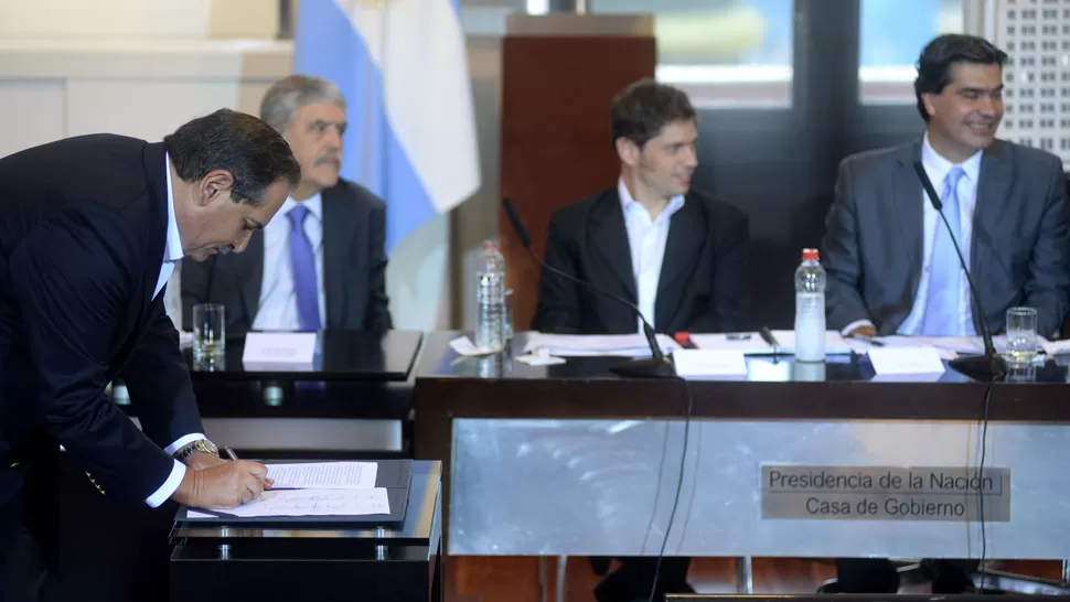LA FIRMA DE ALPEROVICH. El gobernador tucumano rubrica el acuerdo. Detrás aparecen el ministro de Planificación, Julio de Vido, el de Economía, Kicillof, y el jefe de Gabinete, Jorge Capitanich.