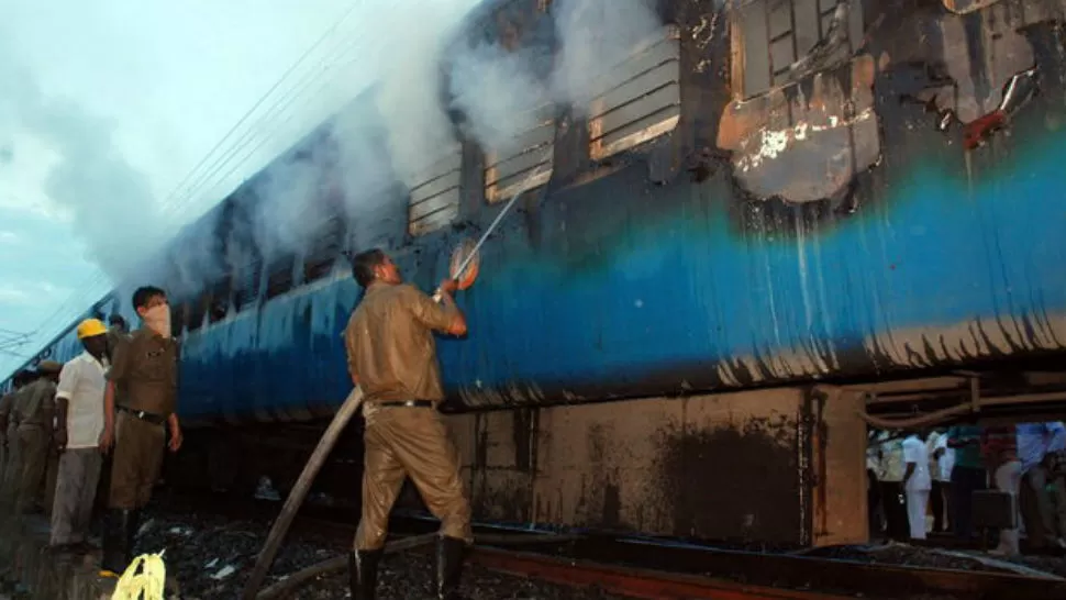 TRABAJO. Bomberos indios extinguen el fuego en un vagón carbonizado del Expreso Tamil Nadu Nueva Delhi-Chennai. FOTO DE TEINTERSA.ES