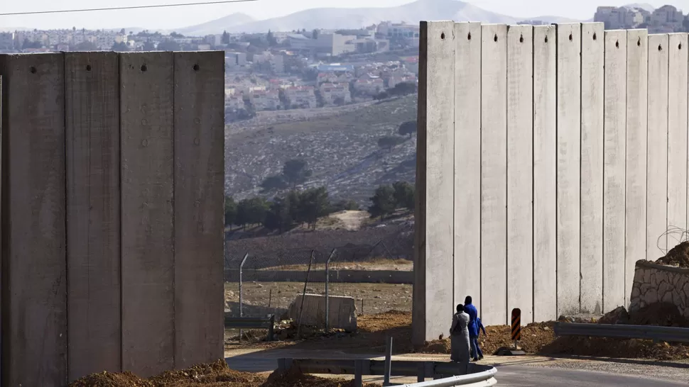 DIVIDIDOS. Un grupo de palestinos pasa por la apertura en el controversial muro que divide Jerusalém. REUTERS