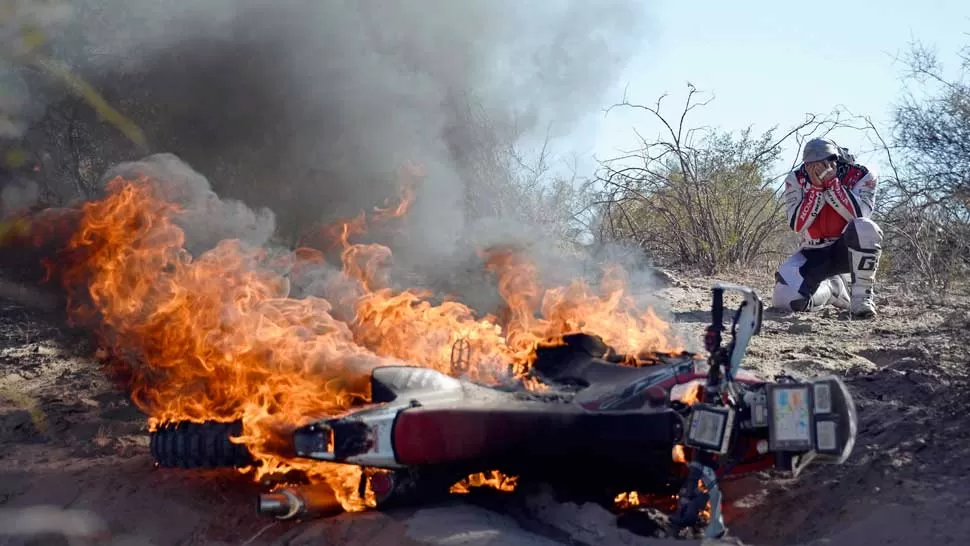 DESCONSUELO. El piloto portugués llora mientras su moto es consumida por las llamas. REUTERS