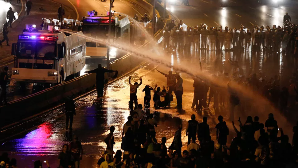 CHOQUE. Las fuerzas de seguridad tiran agua a presión a los manifestantes. REUTERS