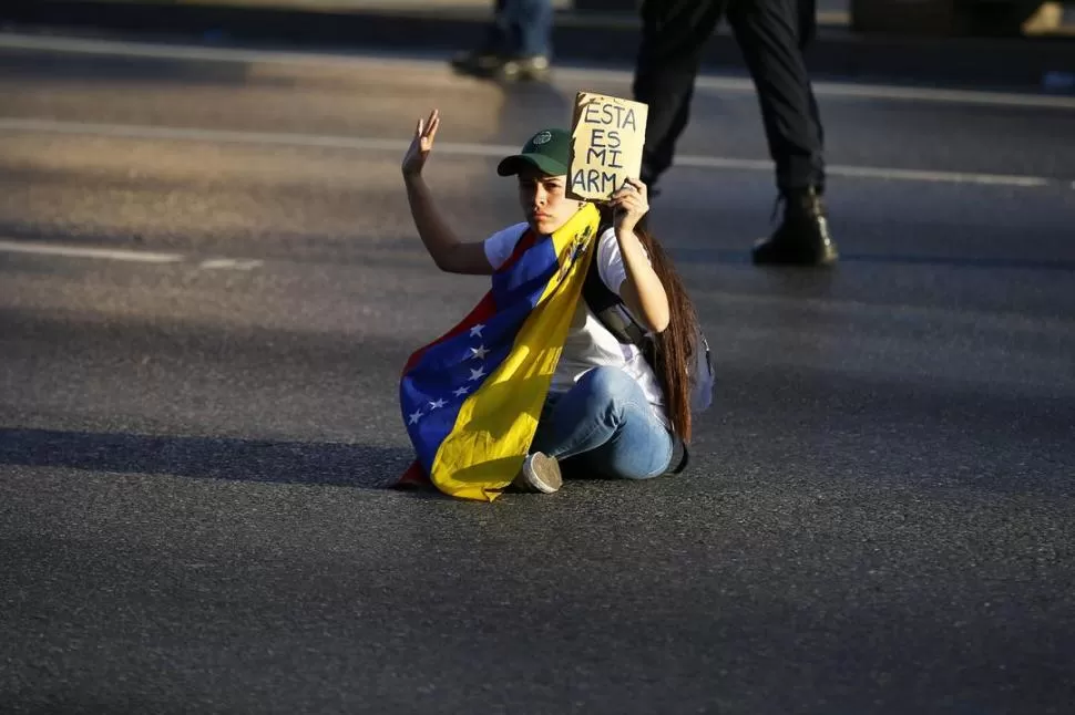 PROTESTA. Una manifestante bloquea la ruta principal de Caracas. reuters