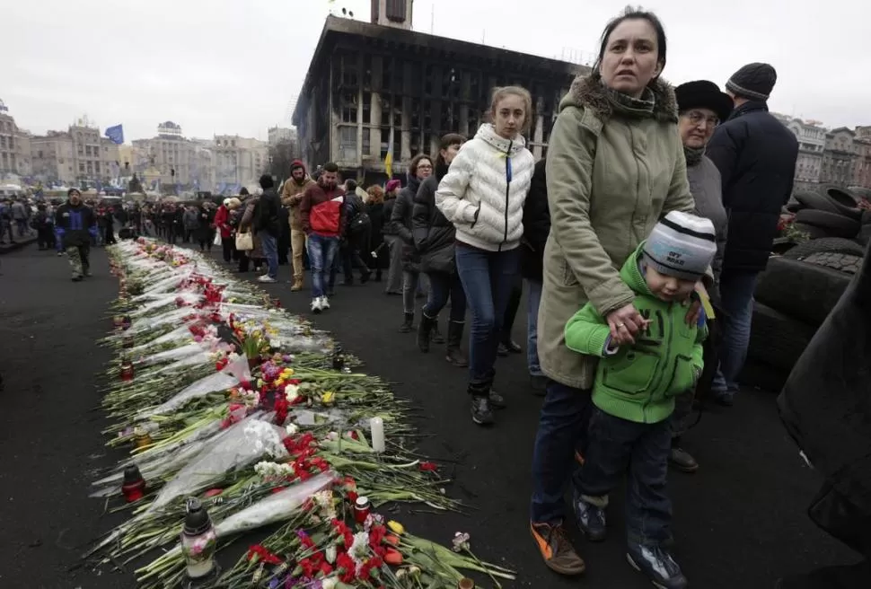 KIEV. Ucranianos caminan entre un cementerio de flores, tras los incidentes. reuters