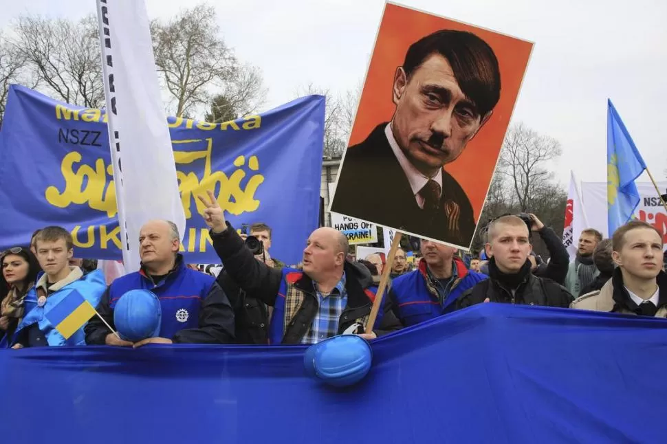 EN VARSOVIA. Polacos protestan contra Putin, caricaturizado como Hitler. REUTERS