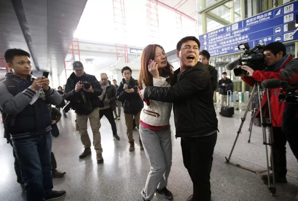 EN PEKÍN. En el aeropuerto de la capital de China, dos familiares de uno de los pasajeros que viajan en el avión desaparecido lloran de desesperación. reuters