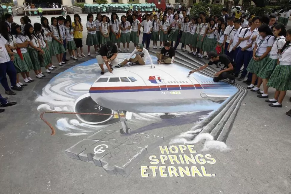 LA ESPERANZA, LO ÚLTIMO QUE SE PIERDE. Artistas pintan el avión en el metro de Manila, frente a estudiantes. FOTOS REUTERS 