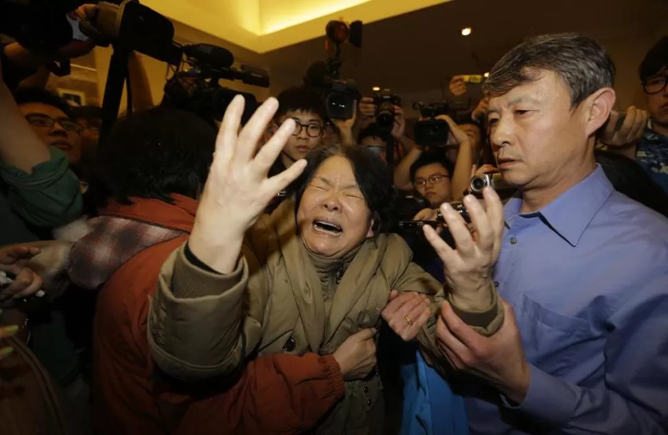 EN PEKÍN. Una pariente de uno de los pasajeros chinos estalla en llanto y es contenida por otros, cuando se enteró del anuncio sobre la caída del avión. reuters