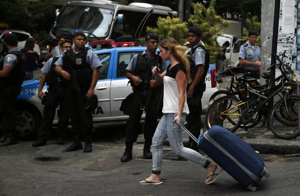 VIGILANCIA. Una turista camina por Copacabana, custodiada por policías reuters