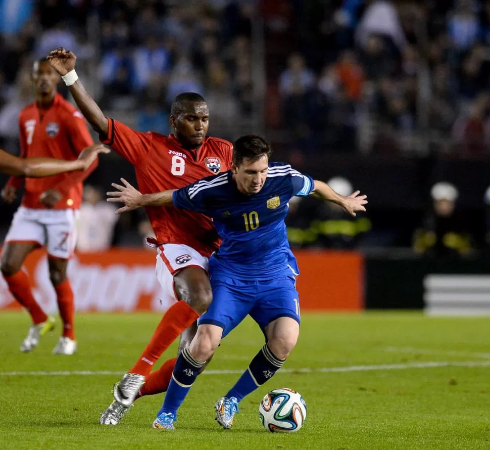 AVANZA CON LA PELOTA DOMINADA. “La Pulga” Messi intenta escaparse de la marca del volante Khaleem Hyland. 