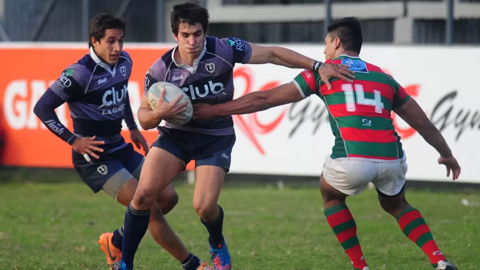 UN PASO AL FRENTE. Gastón Plaza lleva la pelota ante la marca de Macario Villaluenga. Universitario ganó un partido parejo y sigue al acecho del puntero Tucumán Rugby. FOTO DE DIEGO ARAOZ / LA GACETA