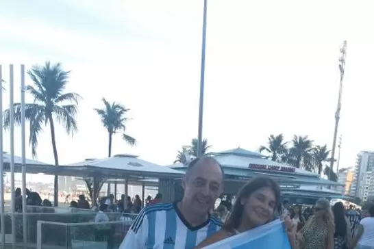EN BRASIL. Adriana y Gustavo Cichini exhiben una bandera con la consigna Hello, que es el nombre del grupo de chat de ella. LA GACETA
