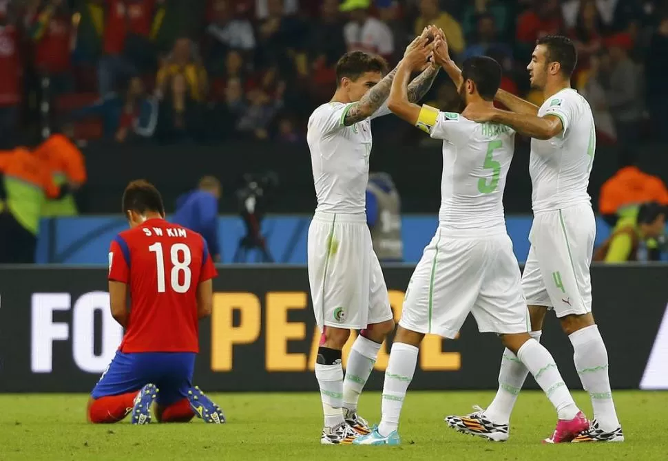 FESTEJO. Los jugadores argelinos festejan tras el triunfo; los coreanos sufren. reuters