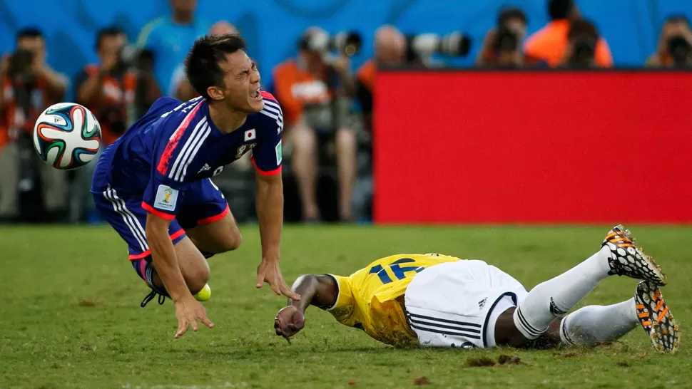 DE CARA AL CÉSPED. El defensor colombiano aterrizó sobre el delantero japonés Okazaki. REUTERS