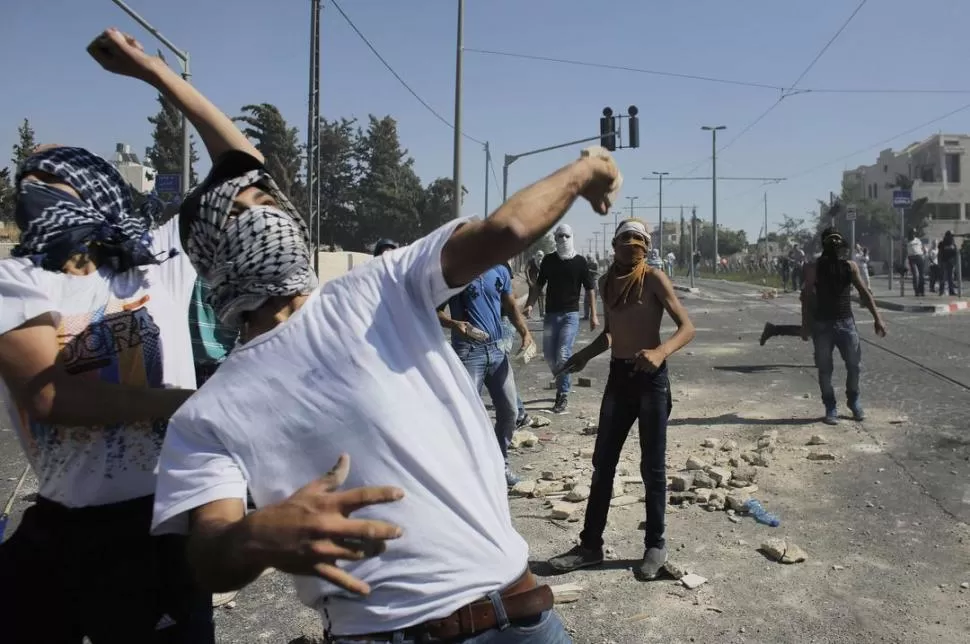 EN SHUAFAT. Palestinos arrojan piedras a la policía israelí, en una nueva jornada de enfrentamientos callejeros. reuters
