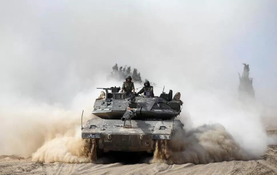 MOVILIZANDO BLINDADOS. Un tanque israelí se desplaza a toda velocidad hacia territorio palestino, como parte de la ofensiva en contra de Hamas. fotos reuters
