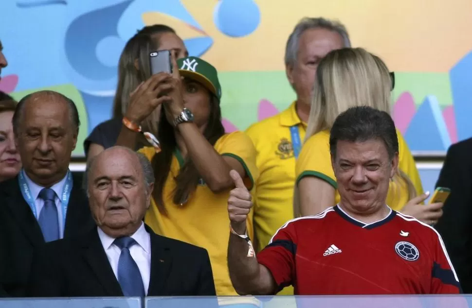 EN CUARTOS. Blatter va a la cancha en Brasil (en este caso aparece junto al presidente de Colombia, Juan Manuel Santos), pero las cámaras de TV no lo enfocan. reuters
