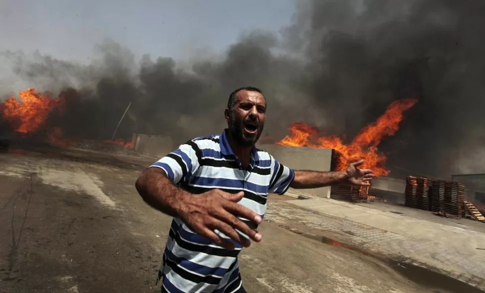 INCENDIO EN UN PARQUE INDUSTRIAL. Un palestino busca ayuda, tras el impacto de una bomba lanzada desde la avión israelí, en el Este de Gaza. reuters