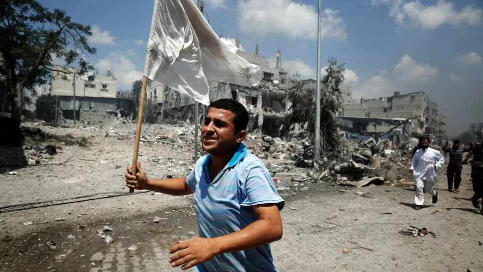 SIN TREGUA. Un palestino huye por las calles de Gaza con una bandera blanca en sus manos. REUTERS