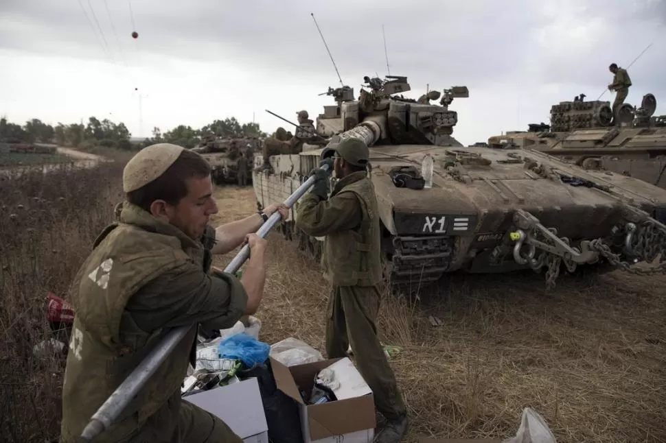 EN LA FRONTERA. Soldados israelíes preparan los tanques para entrar a Gaza. REUTERS