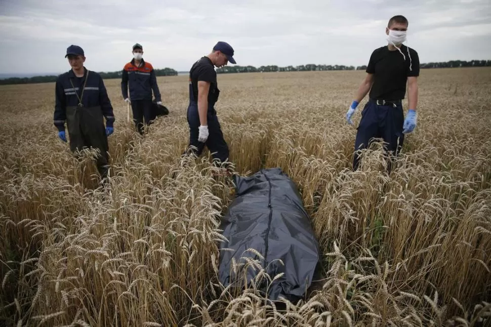 EN GRABOVO. Socorristas ucranianos se aprestan a retirar de la zona donde cayó el Boeing 777-200 uno de los cuerpos encontrados en pleno campo. REUTERS
