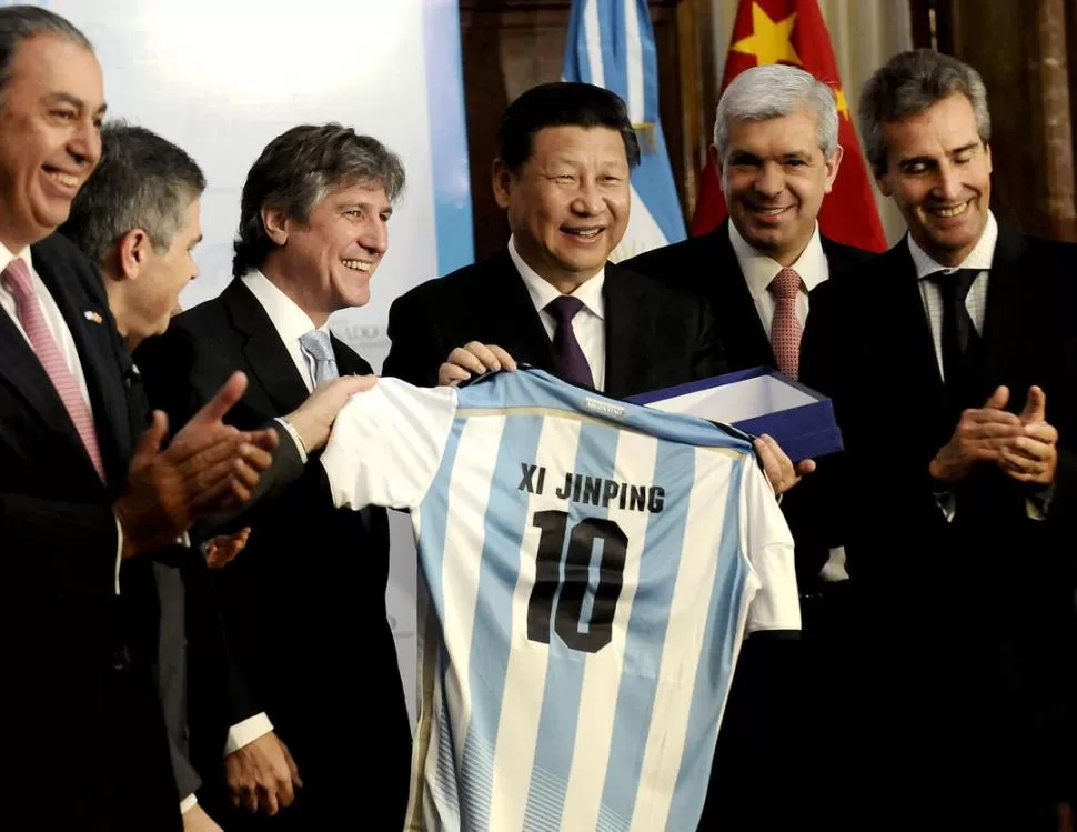 OBSEQUIO. El jefe de Estado chino, flanqueado por Boudou y por Domínguez, recibe una camiseta emblemática de la Selección, con su nombre en ella. DYN