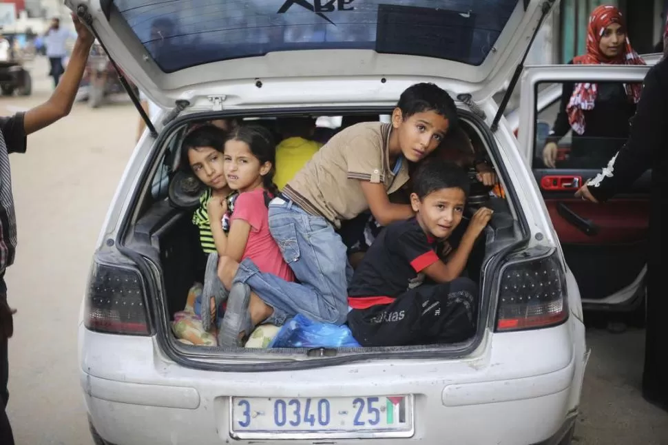 EL SUR DE LA FRANJA. Apretados en el baúl de un auto, varios niños palestinos huyen de Gaza con sus padres. fotos reuters